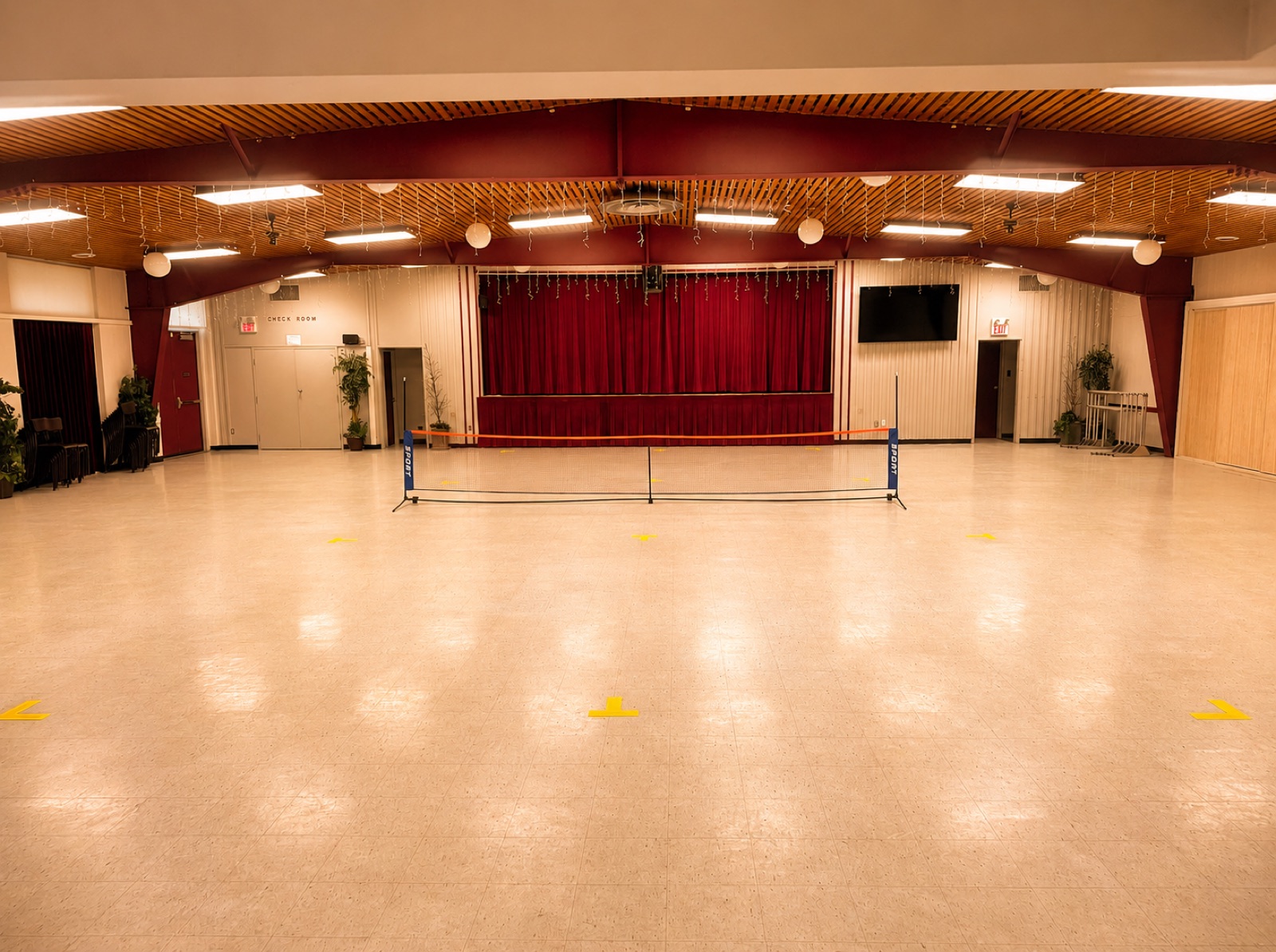 The hall converted into a badminton and pickleball court with a portable net and yellow floor markings