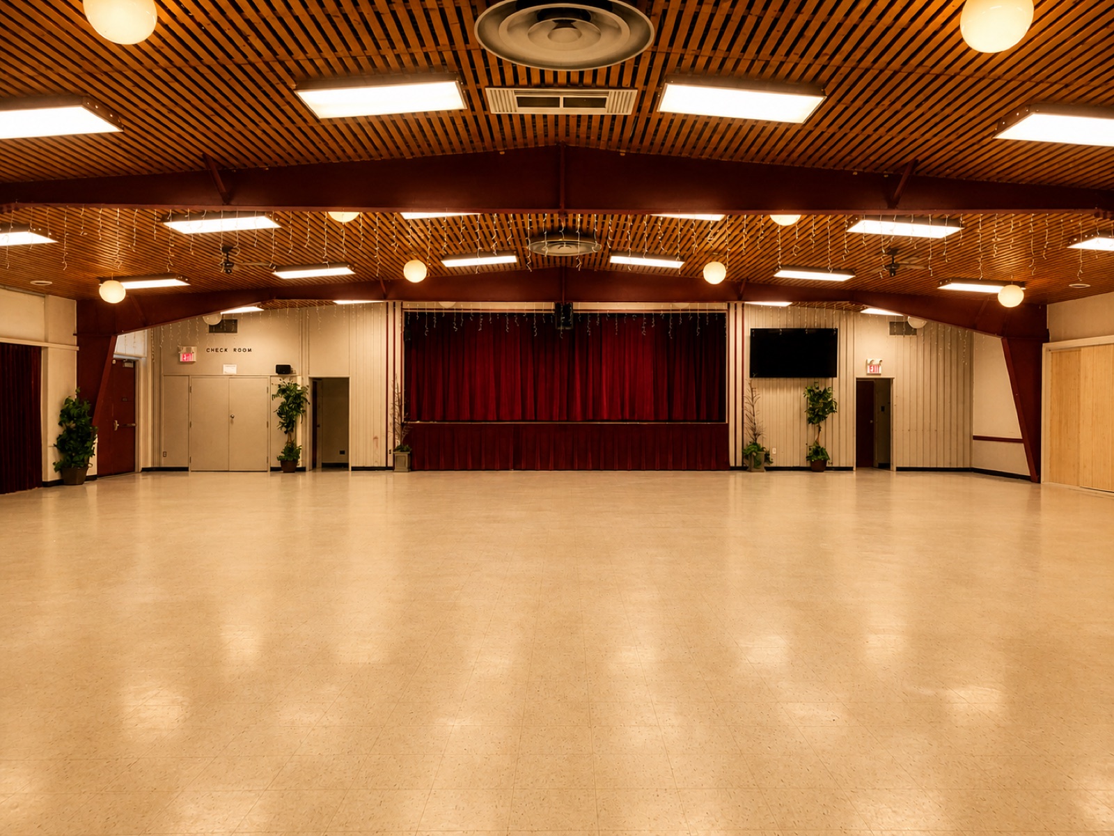 The open floor of All Saints Hall, looking toward the stage and red curtains
